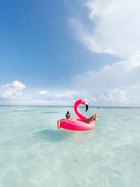 Young woman floating in inflatable ring on sea against sky