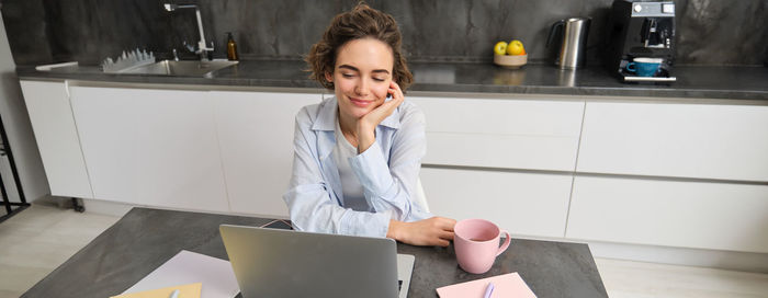 Portrait of young woman using digital tablet at home