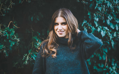 Portrait of smiling young woman standing in forest