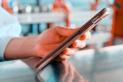 Close-up of person holding smart phone on table