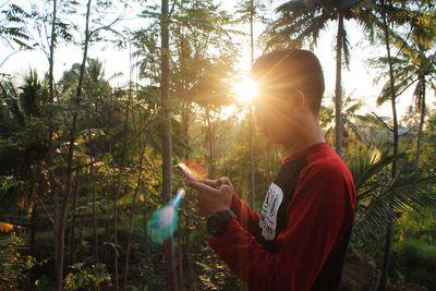 Man standing by trees in forest