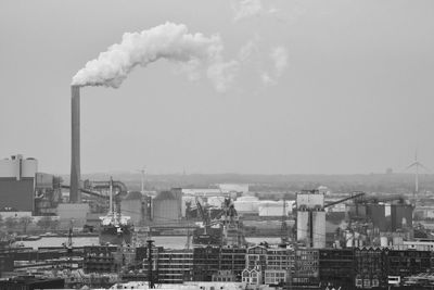 Smoke emitting from factory against sky