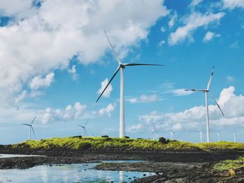 Traditional windmill by sea against sky