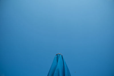High section of umbrella against clear blue sky