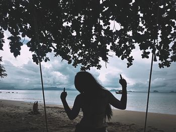 Silhouette man standing at beach against sky