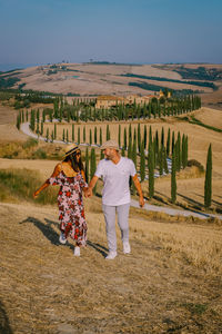 Rear view of couple walking on field