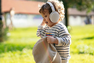 Cute baby wearing headphones while standing at park