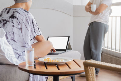 Woman working on vacation behind a laptop with a ocean view