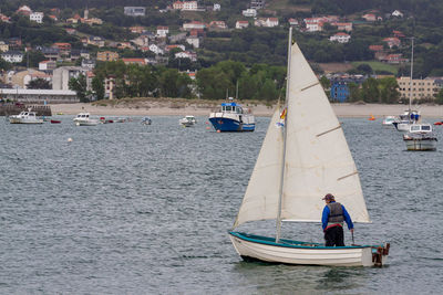 Boats sailing on sea by harbor against sky