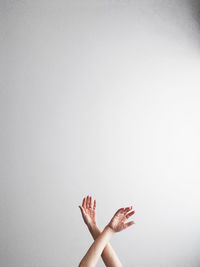 Close up of crossed hands at wrist level against white background with lot of negative space