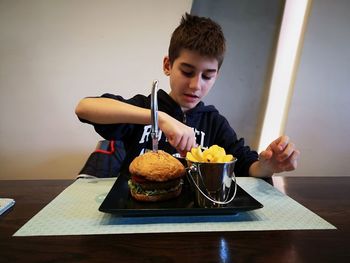 Boy holding food while sitting on table