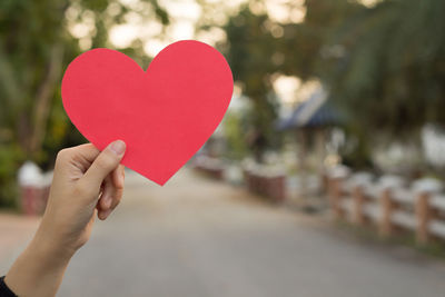 Close-up of hand holding heart shape against blurred background