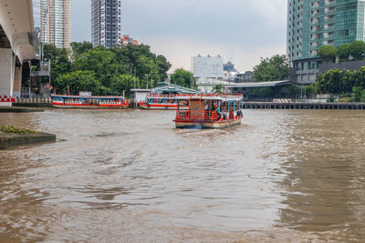 Boat in river against buildings in city