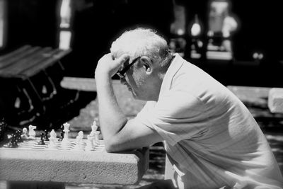 Close-up of man sitting on chess board