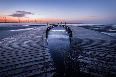 Pier over sea against sky during sunset