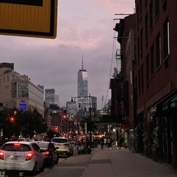 City street amidst buildings against sky at dusk