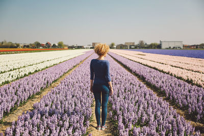 Rear view of woman standing on field against sky