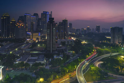 High angle view of illuminated street amidst buildings in city at night