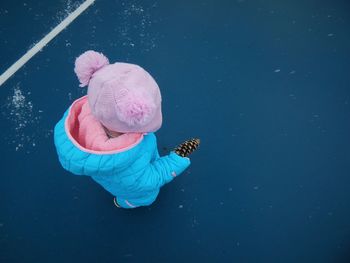 High angle view of baby girl holding pine cone while walking on street