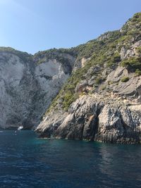 Scenic view of sea and mountains against clear blue sky