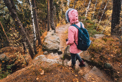 Full length of woman standing amidst trees in forest