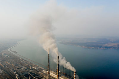 Smoke emitting from factory against sky