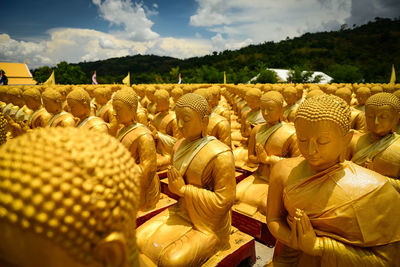 Buddha statues in city against sky