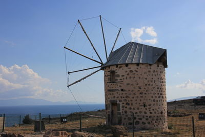 Damaged traditional windmill on field against sky