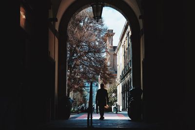Rear view of silhouette man walking by building
