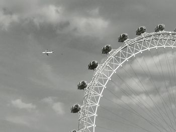 Low angle view of ferris wheel against cloudy sky