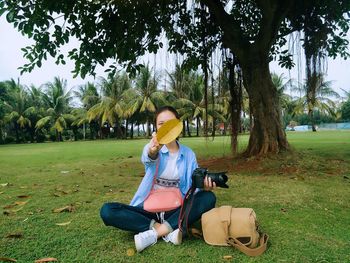 Young woman sitting on tree at park