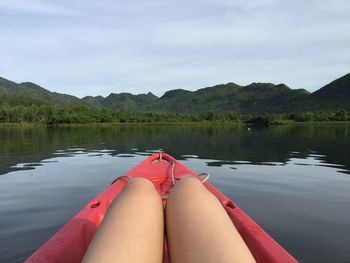 Cropped image of woman sitting on boat in lake against mountains