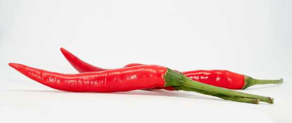 Close-up of red chili peppers against white background