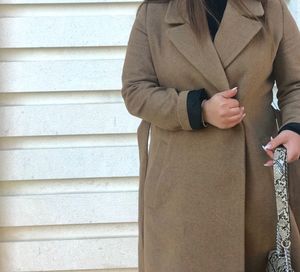 Midsection of woman holding umbrella standing against wall