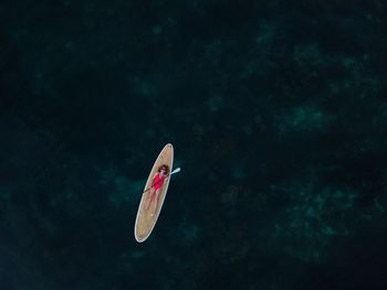 Aerial view of woman lying on paddleboard over sea