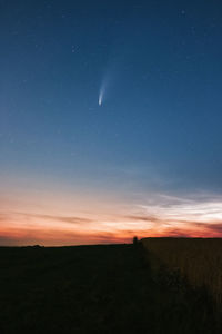 Scenic view of silhouette field against sky with streaking comet at night