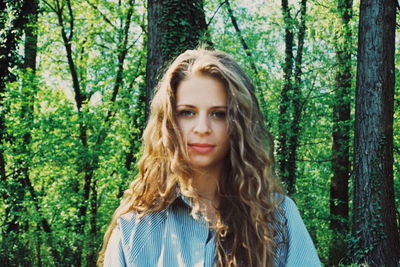 Portrait of young woman against tree trunk in forest