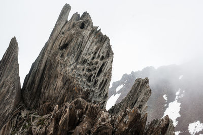 Low angle view of rock formation against sky during winter