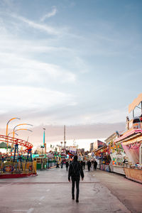 Young man in a colorful funfair/amusement park at sunset