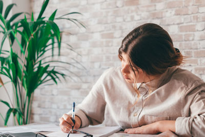 Young woman writing in book at home