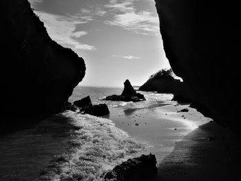 Silhouette rocks on beach against sky