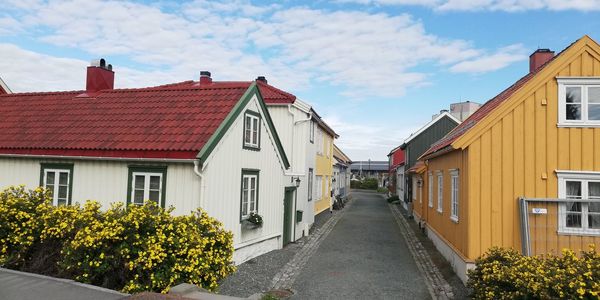 Road amidst houses and buildings against sky