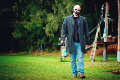 Full length portrait of mature man standing on grassy field