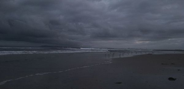 Scenic view of beach against cloudy sky