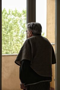 Rear view of man and woman standing by window