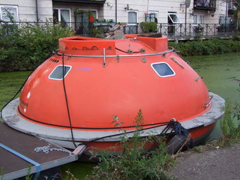 Close-up of red boat moored on grass against trees