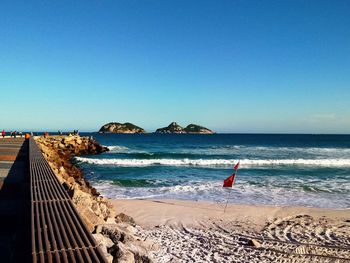 Scenic view of beach against clear blue sky