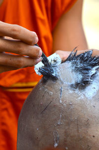 Midsection of man shaving person head