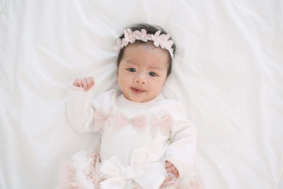 High angle portrait of cute baby girl lying on bed