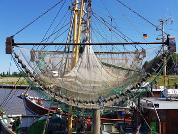 Sailboats moored at harbor against blue sky